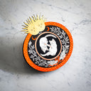 Black and orange ink illustration of 2 cats, floating opposite one another like yin & yang. They are in a circle surrounded by floral patternings. 2 gold suns are at the top of the piece.