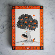 Illustration using only black and orange paint/ink of a woman in a hoop dress with an apple atop her head, peeking out from behind a large apple tree. Apples are on the ground and the piece has a drawn flower and geometric pattern border.