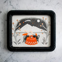 Black ink illustration with subtle orange accent coloring of 2 people sitting at a table with a patterned orange tablecloth. The both drink steaming tea and sit outdoors near a mountain range and look up at a shooting star. 