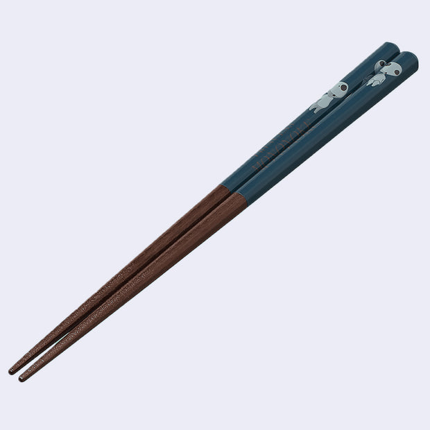 Pair of dark grain wooden chopsticks with the top half a deep teal color and small drawing of Kodamas on them from Princess Mononoke.