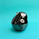 Ceramic sculpture of a puffin with a very rounded, chubby body. It sits with one of its legs lifted.
