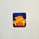 Illustration of a yellow cartoon character on a dark blue background on a tiny tiny wood panel.