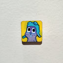 Illustration on tiny wood panel of a gray cartoon squirrel. 