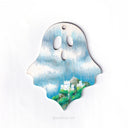 Ghost shaped wood panel with an illustration of a castle sitting atop the side of a hill with lush greenery and a blue sky with many clouds.