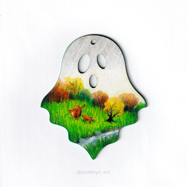 Ghost shaped wood panel with an illustration of a grassy pasture lined with autumn colored trees, 2 cows graze in it. The sky is gray as though it is rainy.