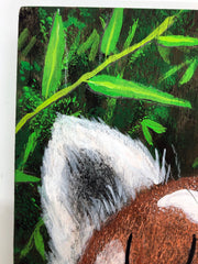 Illustrative style painting of a cute, red panda with large closed eyes and a smiling tongue out expression. Only its head is visible but it takes up most of the surface, with bamboo behind it.