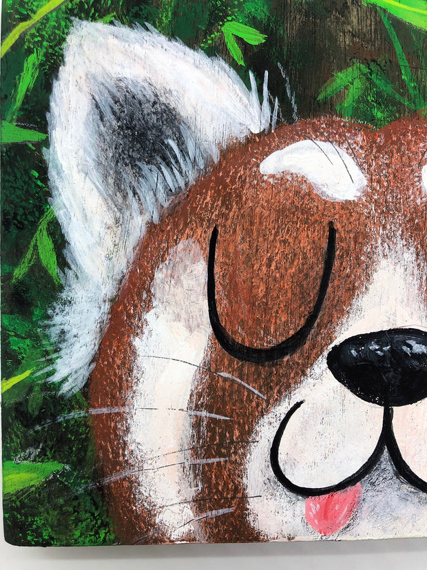 Illustrative style painting of a cute, red panda with large closed eyes and a smiling tongue out expression. Only its head is visible but it takes up most of the surface, with bamboo behind it.