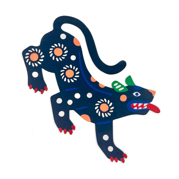 Die cut, brightly painted wooden sculpture of a folk art style panther, dark blue with peach and white patterning on its body. It has red nails and a red tongue, which extends outwards.