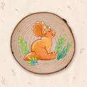 A circular wooden slice featuring a colorful painted illustration of a baby triceratops dinosaur surrounded by green plants, set against a light beige background with subtle botanical patterns.