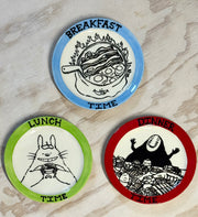 Three decorative plates, each with food related imagery and a Studio Ghibli character.
