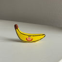Small ceramic sculpture of a cartoon banana with a cute smiley face.