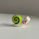 Tiny ceramic sculpture of a green cartoon snail.