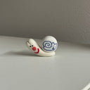 Tiny ceramic sculpture of a snail with a snail design on its shell.