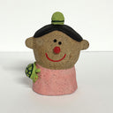 Ceramic sculpture of a boy's top half, without arms. He wears a pink shirt, has a tiny green beanie and a small turtle crawling on his shoulder.