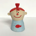 Ceramic sculpture of a girl's top half, without arms. She wears a blue sweater with a goldfish design. Her red hair is in a top ponytail.