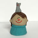 Ceramic sculpture of a girl's top half, without arms. She wears a blue sweater and has a gray cat sitting atop her head.