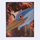 Illustration of an animated character looking fiercely at the viewer. In front of its face, blocking most of it, is a blue and white crane with a yellow eye with a red surrounding area.