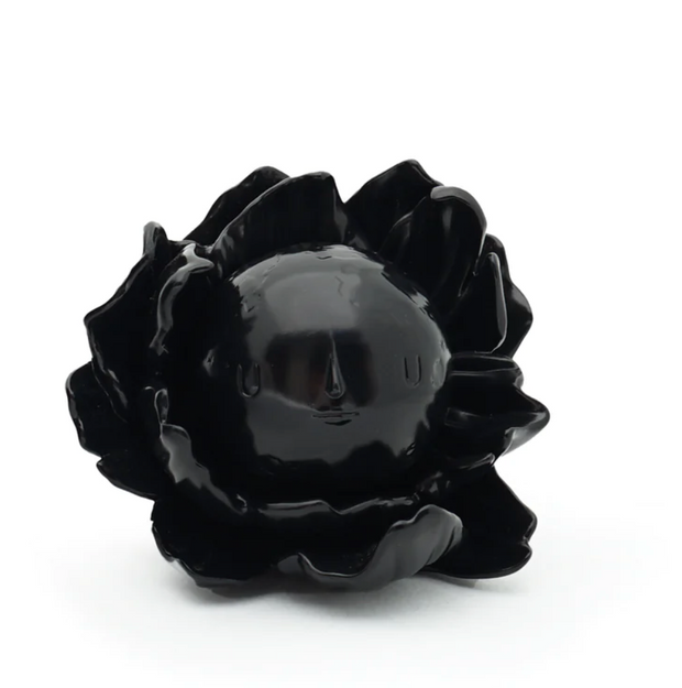 Moonflower toy by yoskay Yamamoto is black flower with a removable moon with a face in it that's the middle of the flower. It's all black.