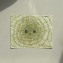 Green marker illustration of a linear smoke like pattern, with a set of 2 small eyes and a tiny mouth.