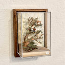 Mixed media sculpture of a person sitting on the branch of a tree, playing a sound bowl with small owls around them.