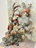 Mixed media sculpture of a person sitting on the branch of a tree, playing a sound bowl with small owls around them.