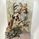 Mixed media sculpture of a person sitting on the branch of a tree, playing a sound bowl with small owls around them.