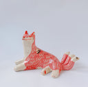 Ceramic figurine of a white and pink fox with 3 tails and patterned fur. It has red "wind" designs on it and gold painted accents.