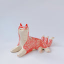 Ceramic figurine of a white and pink fox with 3 tails and patterned fur. It has red "wind" designs on it and gold painted accents.