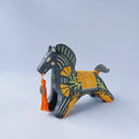Black matte ceramic figure of a horse with carved decorative elements of orange poppy flowers, orange flames and an orange blanket. It has an orange tassel in its mouth.