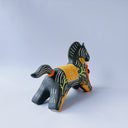 Black matte ceramic figure of a horse with carved decorative elements of orange poppy flowers, orange flames and an orange blanket. It has an orange tassel in its mouth.