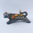 Black sgraffito ceramic sculpture of a tiger, with a long body and a carved pattern of orange poppy flowers.