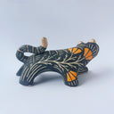 Black sgraffito ceramic sculpture of a tiger, with a long body and a carved pattern of orange poppy flowers.
