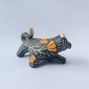 Black sgraffito ceramic sculpture of a tiger, with a long body and a carved pattern of orange poppy flowers.