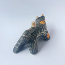 Black sgraffito ceramic sculpture of a tiger, with a long body and a carved pattern of orange poppy flowers.