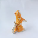 Glossy ceramic sculpture of a white and orange tiger, leaning back on its hindlegs with its front legs up and its head thrown back. It has an orange poppy flower pattern on its back.