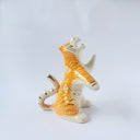 Glossy ceramic sculpture of a white and orange tiger, leaning back on its hindlegs with its front legs up and its head thrown back. It has an orange poppy flower pattern on its back.