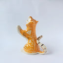 Glossy ceramic sculpture of a white and orange tiger, leaning back on its hindlegs with its front legs up and its head thrown back. It has an orange poppy flower pattern on its back.
