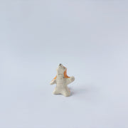 Very small ceramic sculpture of a white and orange tiger, leaning back on its hindlegs with its front legs up and its head thrown back.
