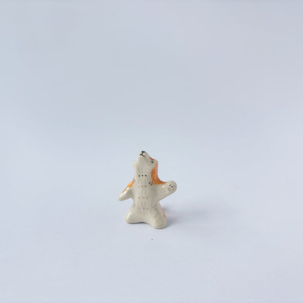 Very small ceramic sculpture of a white and orange tiger, leaning back on its hindlegs with its front legs up and its head thrown back.
