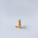 Very small ceramic sculpture of a white and orange tiger, leaning back on its hindlegs with its front legs up and its head thrown back.