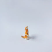 Very small ceramic sculpture of a white and orange tiger, leaning back on its hindlegs with its front legs up and its head thrown back.