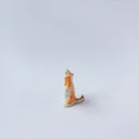Very small ceramic sculpture of a white and orange tiger, leaning back on its hindlegs with its front legs up and its head thrown back.