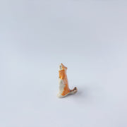 Very small ceramic sculpture of a white and orange tiger, leaning back on its hindlegs with its front legs up and its head thrown back.