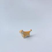 Very small ceramic sculpture of an orange and white tiger with gold detailing,