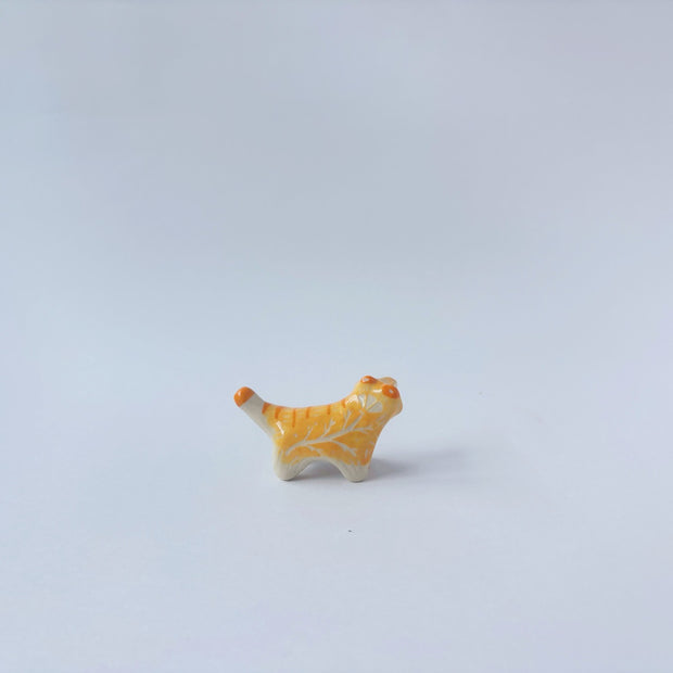 Very small ceramic sculpture of an orange and white tiger with gold detailing,