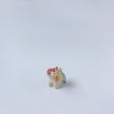Very small ceramic sculpture of a tiger with a white underbelly and rainbow coloring on its back with gold detailing.