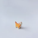 Very small ceramic sculpture of a tiger with a white underbelly and orange fur with red stripes, gold detailing and white carved poppy flowers. It is in a roaring stance.