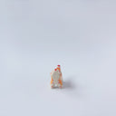 Very small ceramic sculpture of a tiger with a white underbelly and orange fur with red stripes, gold detailing and white carved poppy flowers. It is in a roaring stance.