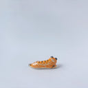 Very small glossy ceramic sculpture of a tiger, laying down asleep. It has a carved poppy flower pattern and gold detailing.