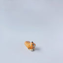 Very small glossy ceramic sculpture of a tiger, laying down asleep. It has a carved poppy flower pattern and gold detailing.